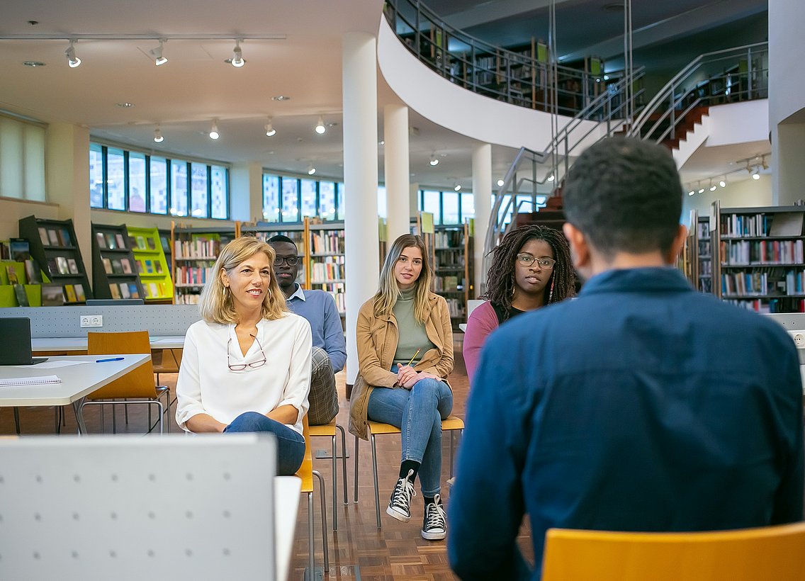 Gruppe sitzt in Bibliothek